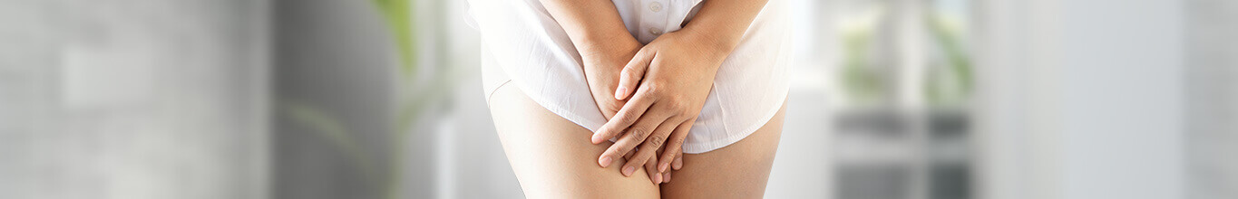 Menü-Teaser: Blase - Frauenkörper in weißem Hemd  hält die Hände vor den Schritt